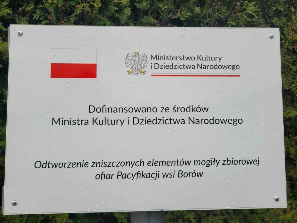 
                                                    Tablica informacyjna z polską flagą i godłem, informująca o dofinansowaniu przez Ministerstwo Kultury i Dziedzictwa Narodowego odbudowy mogiły zbiorowej w Borowie.
                                                