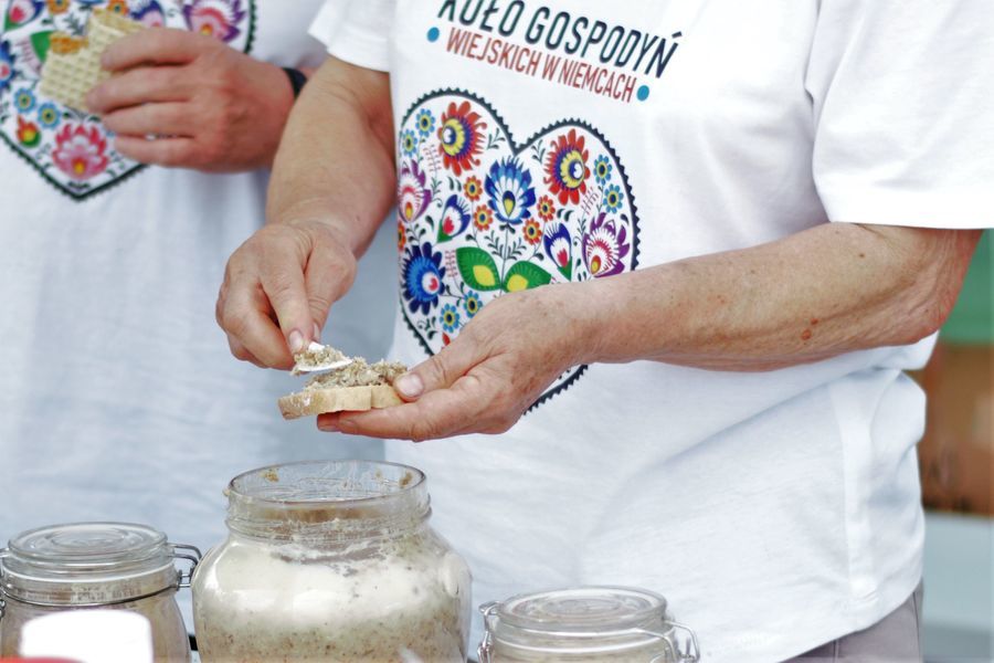 Na zdjęciu widać słój ze smalcem i dłonie kobiety, które smarują chleb.