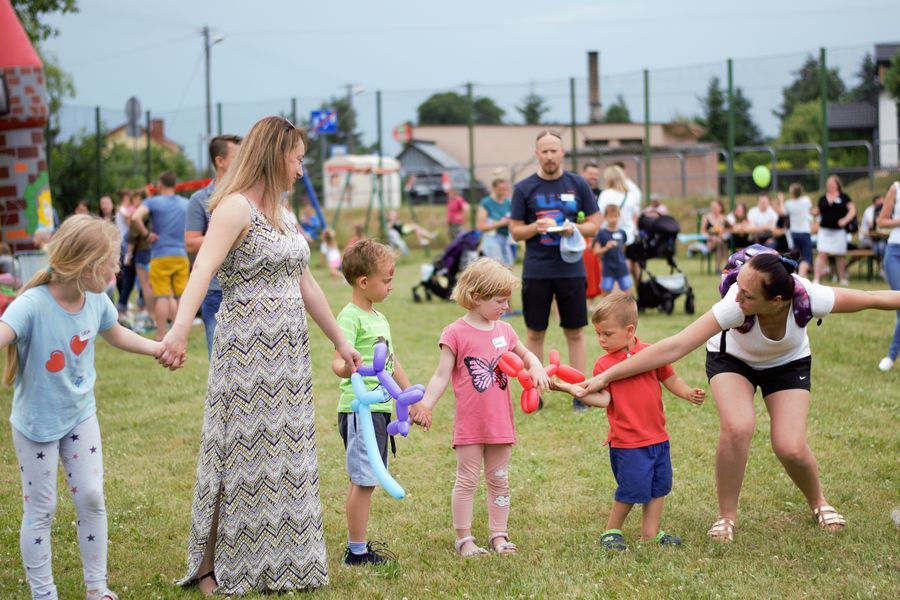Na zdjęciu widać czworo dzieci i dwie kobiety. Wszyscy trzymają się za ręce, dzieci mają także balony w dłoniach.
