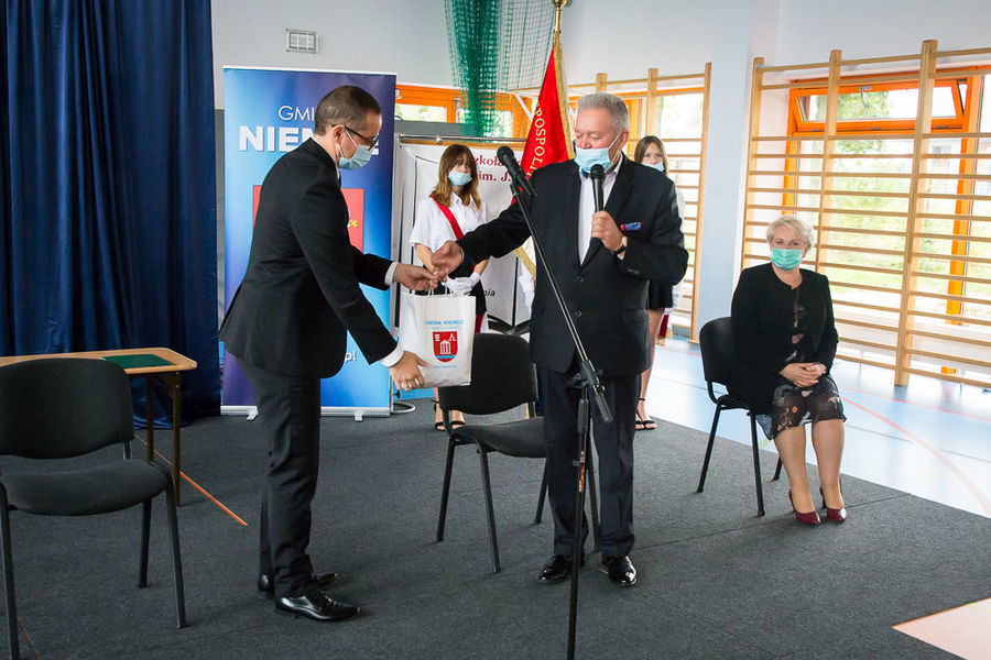 Na zdjęciu wójt przekazuje dyrektorowi torbę z cukierkami dla uczniów