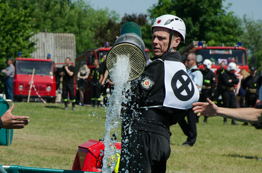 Na zdjęciu strażak trzymający wąż do wody  