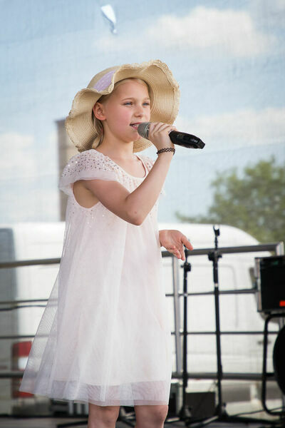 Dziewczynka w kapeluszu śpiewająca na scenie