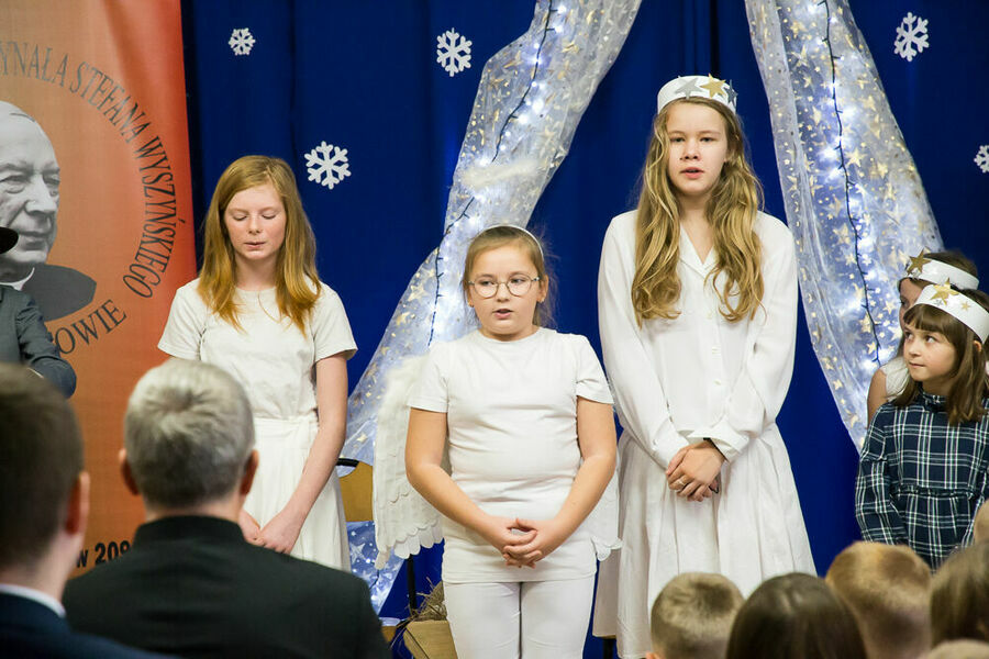 trzy dziewczynki przebrane za aniołki podczas śpiewania kolędy