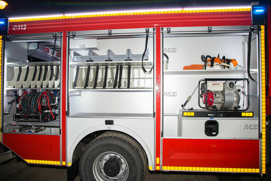 Bok samochodu strażackiego z otwartym schowkiem na niezbędne narzędzia