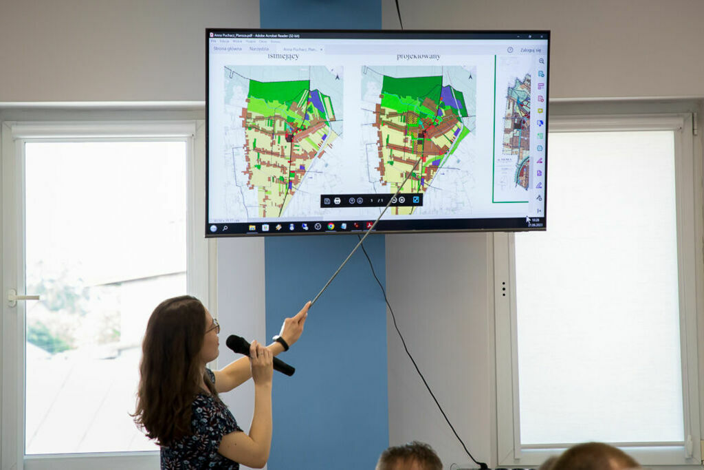 kobieta wskazuje punkt na mapie wyświetlającej się na telewizorze