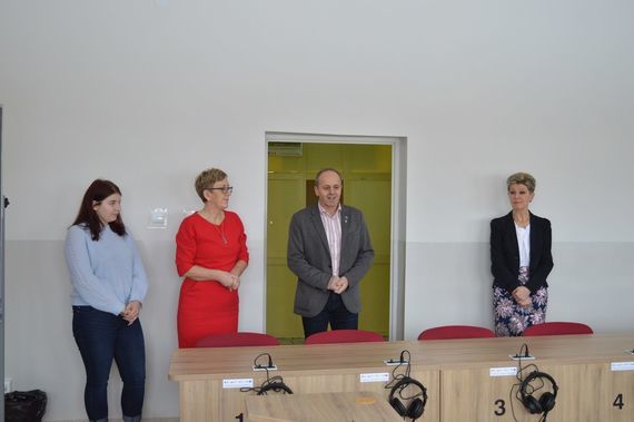 
                                                    4 osoby stojące za biurkiem
                                                