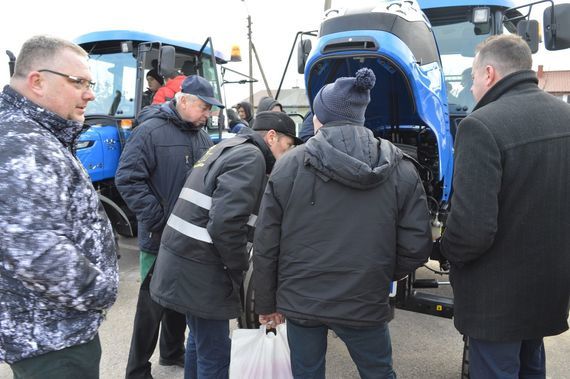 
                                                    Grupa ludzi przy niebieskich ciągnikach
                                                