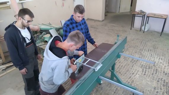 
                                                    Grupa osób przy giętarce blachy
                                                
