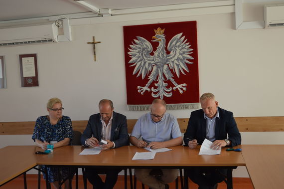 
                                                    Ludzie podpisujący dokumenty na tle godła
                                                