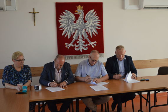 
                                                    Ludzie podpisujący dokumenty na tle godła
                                                
