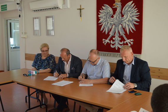 
                                                    Ludzie podpisujący dokumenty na tle godła
                                                