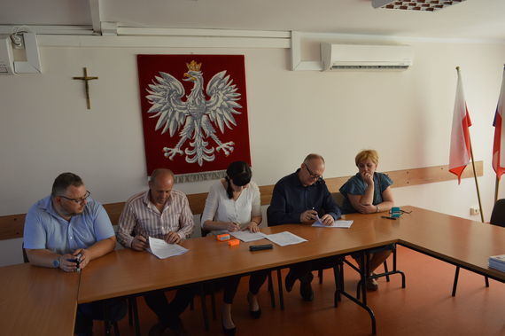 
                                                    Ludzie podpisujący dokumenty na tle godła
                                                