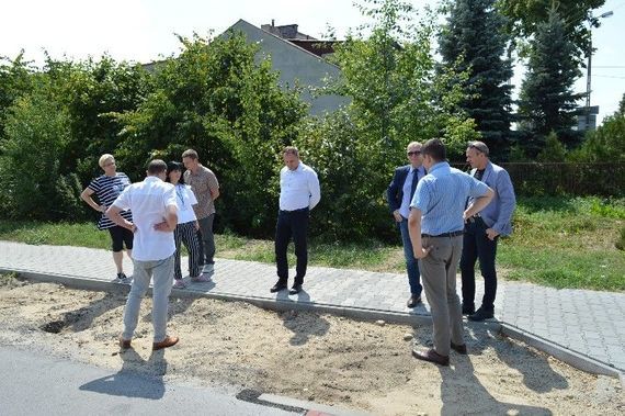 
                                                    Grupa osób stojących na chodniku
                                                