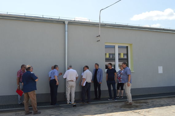 
                                                    Grupa ludzi przy ścianie nowego budynku
                                                