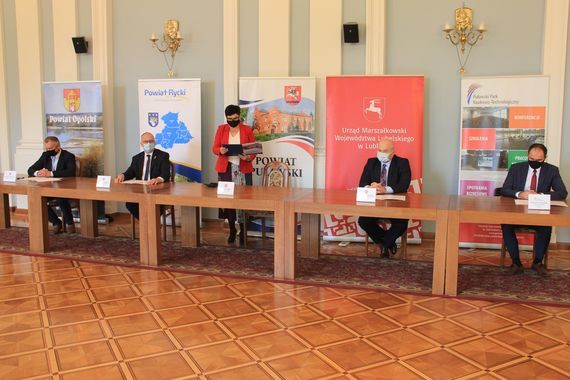 
                                                    Zdjęcie uczestników spotkania na tle rollupów
                                                