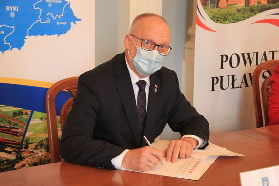 
                                                    Zdjęcie uczestników spotkania na tle rollupów
                                                