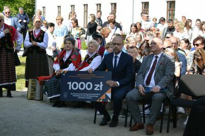 
                                                    Na pierwszym planie osoba z nagrodą, w tle uczestnicy festiwalu.
                                                