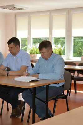 
                                                    Uczestnicy spotkania przy dokumentach
                                                