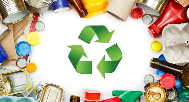 Opis alternatywny: Zdjęcie przedstawia różne przedmioty nadające się do recyklingu, takie jak puszki, butelki plastikowe i szklane, pojemniki, tuby i kartony rozłożone wokół zielonego symbolu recyklingu na białym tle.