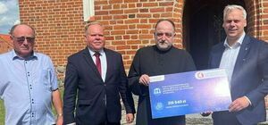 Zdjęcie przedstawia przekazanie symbolicznego czeku przez Ministra dla Proboszcza Kościoła w Rakowcu