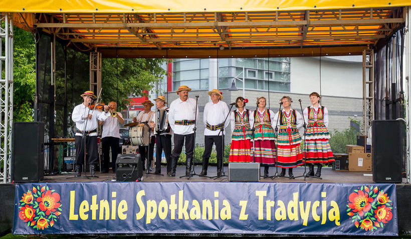 Na zdjęciu zespół ludowy na scenie z napisem Letnie spotkania z Tradycją