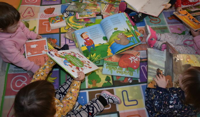 Na zdjęciu dzieci oglądające książeczki.