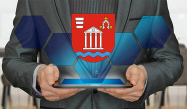 Grafika przedstawia człowieka trzymającego tablet oburącz oraz Herb Gminy Niemce