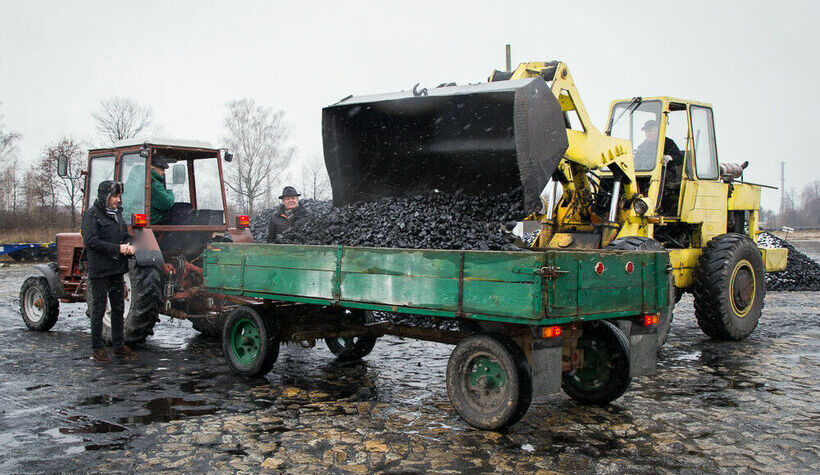 Traktor z przyczepą na którą jest ładowany węgiel