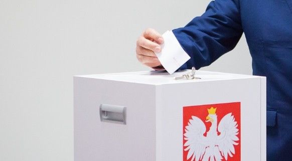 urna wyborcza i ręka wrzucająca kartę do głosowania