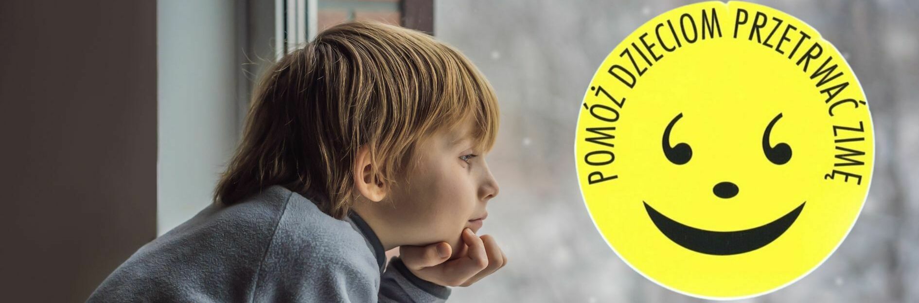 Dziecko spogląda przez okno obok naklejki z uśmiechniętą buźką i napisem "Pomóż dzieciom przetrwać zimę".