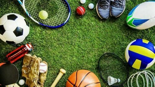 Przyrząd do gier zespołowych leżące na murawie: piłki, buty sportowe, paletki, rakiety do tenisa
