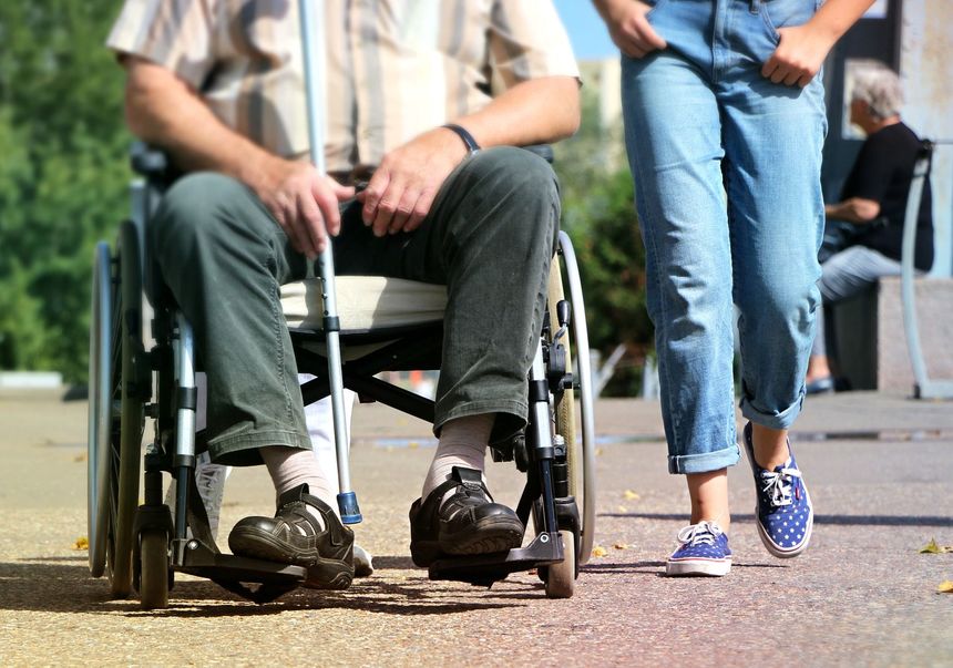 mężczyzna na wózku inwalidzkim w towarzystwie opiekuna