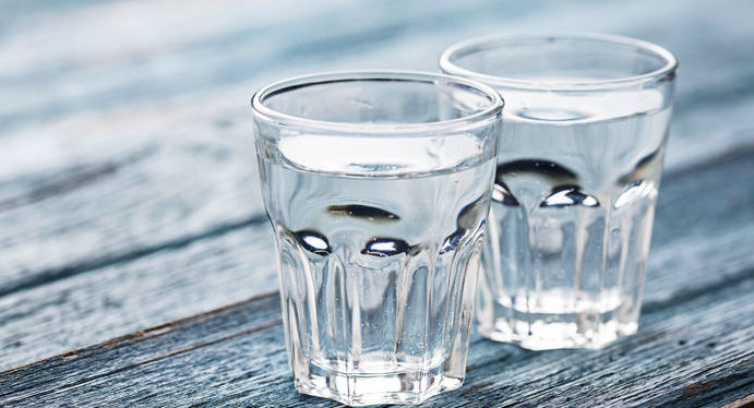 Grafika przedstawia dwie szklanki wody stojące na stole