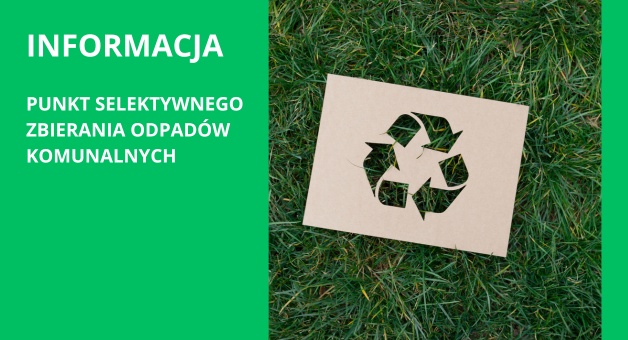 Zdjęcie kartonowej tabliczki z symbolem recyklingu na trawniku, z napisem "INFORMACJA PUNKT SELEKTYWNEGO ZBIERANIA ODPADÓW KOMUNALNYCH" na zielonym tle.