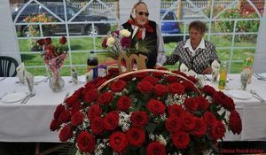 Pani Marianna Borek  z najbliższą rodziną za stołem z pieksnym bukietem róż 