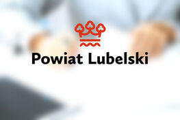 Logo Powiatu Lubelskiego na rozmazanym tle
