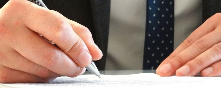 Dłonie osoby podpisującej dokument.
