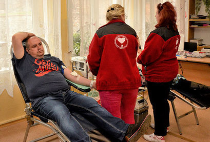 Osoba oddająca krew  i dwie panie przy urządzeniu z krwi