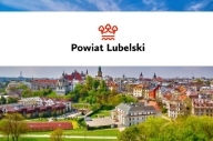 Logo Powiatu Lubelskiego na białym tle. Pod tłem zdjęcie Lublina.
