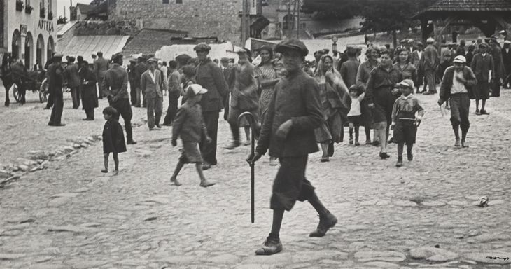 Stare, czarno-białe zdjęcie kazimierskiego Rynku. Tłum ludzi. Na pierwszym planie uśmiechnięty młody chłopak z laską
